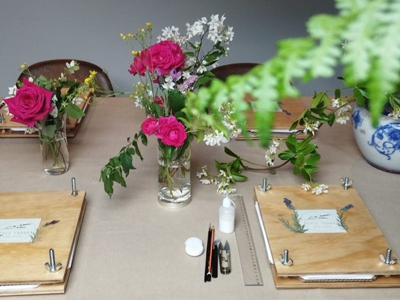 Mesa preparada para el taller de arte floral con flores y prensas